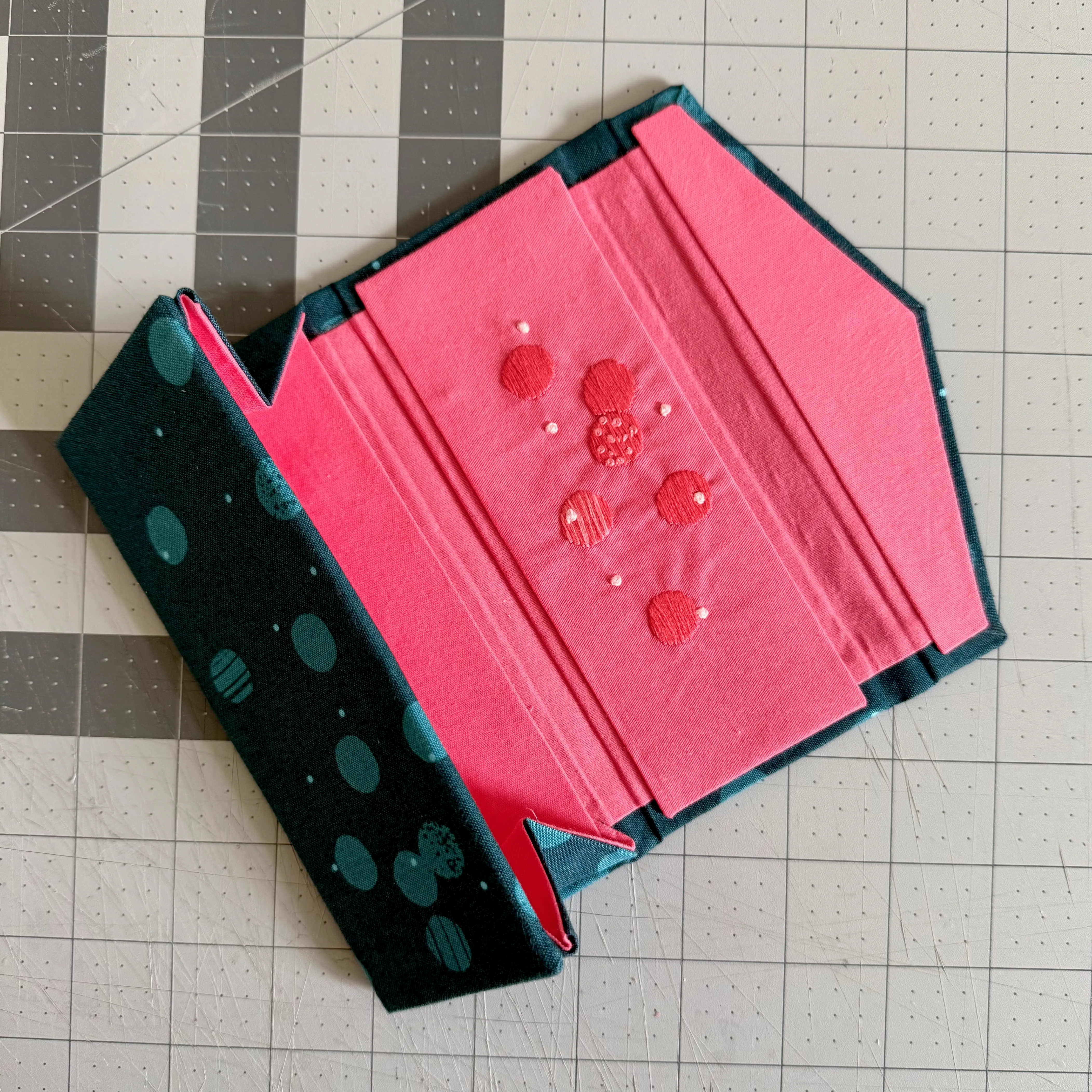 Open sunglasses case with embroidered pink lining panels being assembled