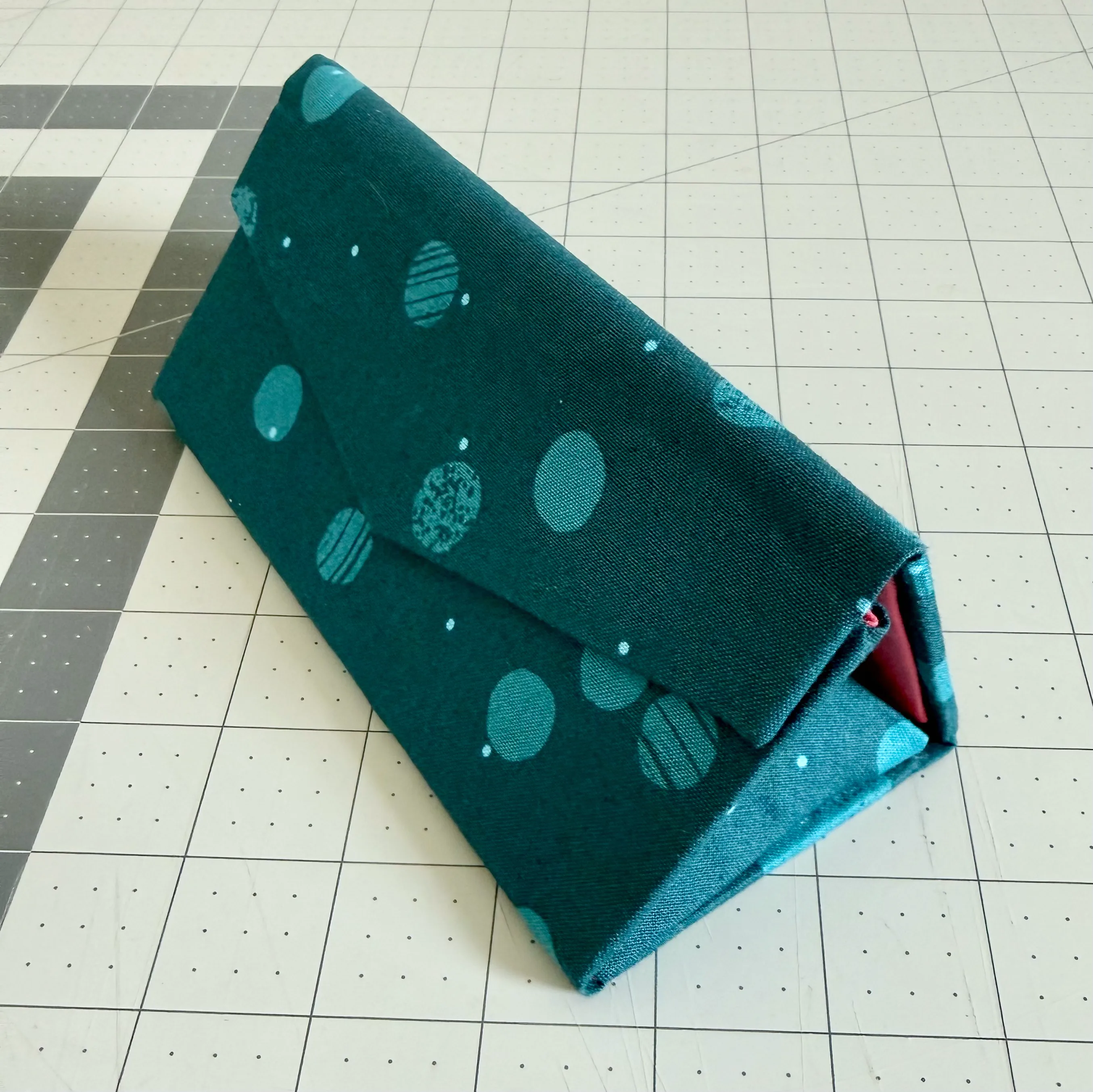 Assembled sunglasses case covered in dark teal bubble-patterned fabric