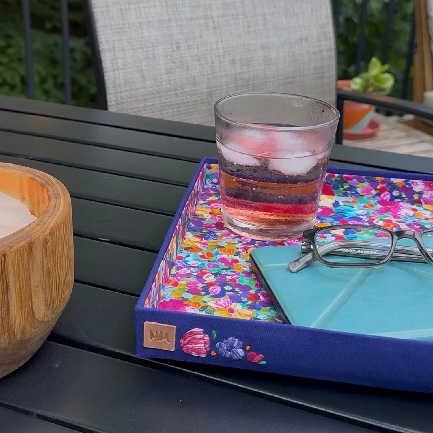Finished floral valet tray holding a drink, glasses, and a tablet outdoors