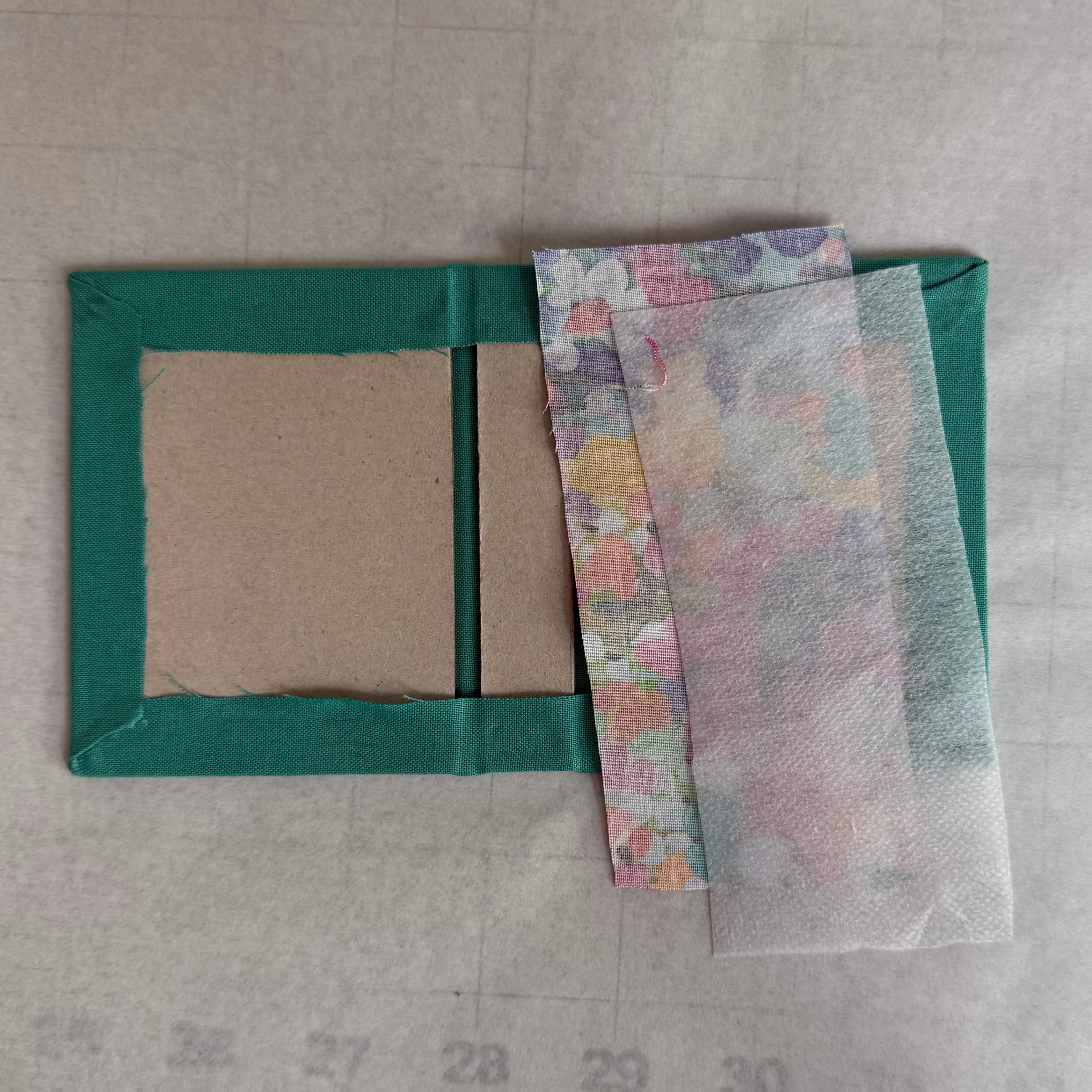 Interior fabric and iron-on interfacing beside the wrapped hinge boards